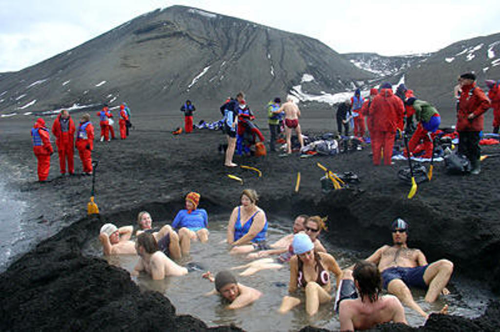 Reizigers nemen een warm bad in een gegraven poel op Antarctica, tijdens de expeditie Crossing the Circle.