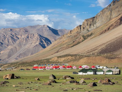 Tentenkamp in de bergen van Spiti & Ladakh, met kleurrijke tenten op een groene vlakte.