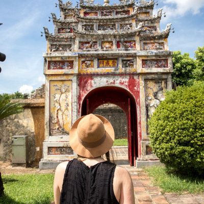Reiziger bij de kleurrijke toegangspoort van de Keizerlijke Stad in Hué tijdens een fietsvakantie in Vietnam.