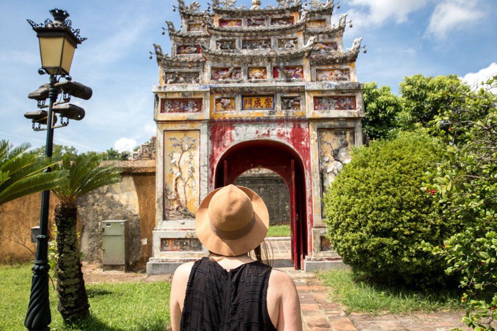 Reiziger bij de kleurrijke toegangspoort van de Keizerlijke Stad in Hué tijdens een fietsvakantie in Vietnam.