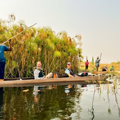 Boottocht door de Okavango Delta tijdens groepsrondreis Zuidelijk Afrika, met reizigers in een mokoro tussen riet.