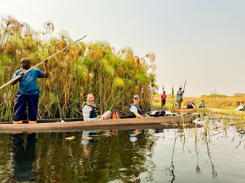 Boottocht door de Okavango Delta tijdens groepsrondreis Zuidelijk Afrika, met reizigers in een mokoro tussen riet.