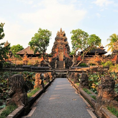 Tempelcomplex op Bali met stenen beelden langs een pad door een lotusvijver, tijdens familiereis Java en Bali.