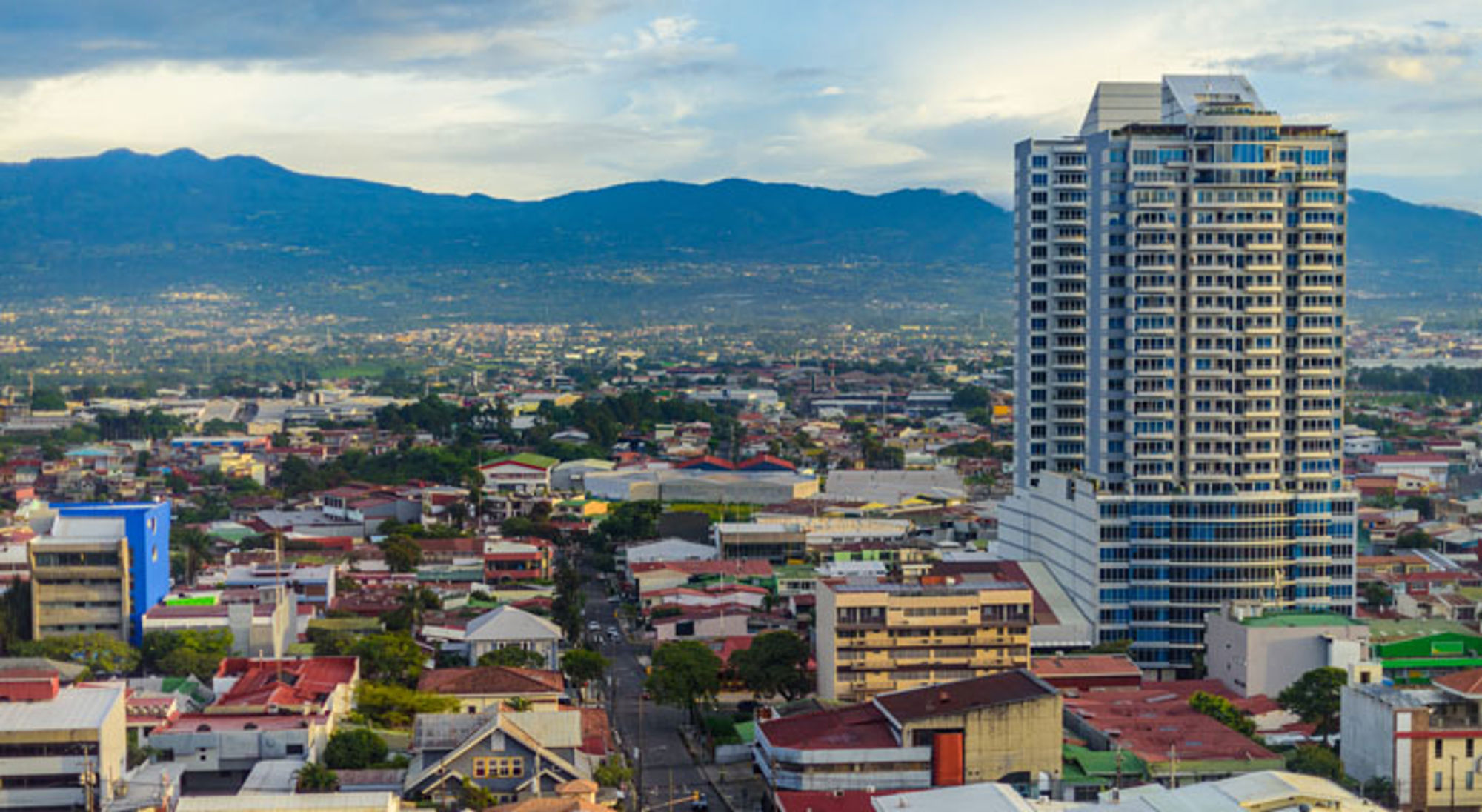 Skyline van San José, Costa Rica, met moderne hoogbouw en bergen op de achtergrond.