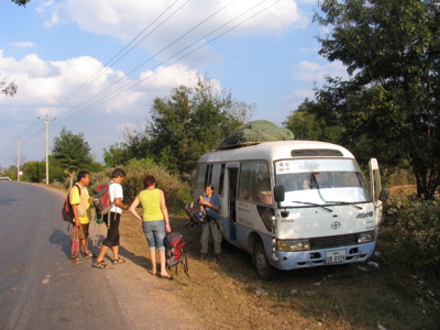 Reizigers met rugzakken stappen in een minibus langs de weg tijdens de route Laos & Cambodja.