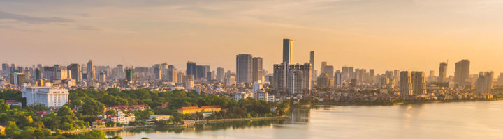 Skyline van Hanoi bij zonsondergang met het West Lake op de voorgrond.