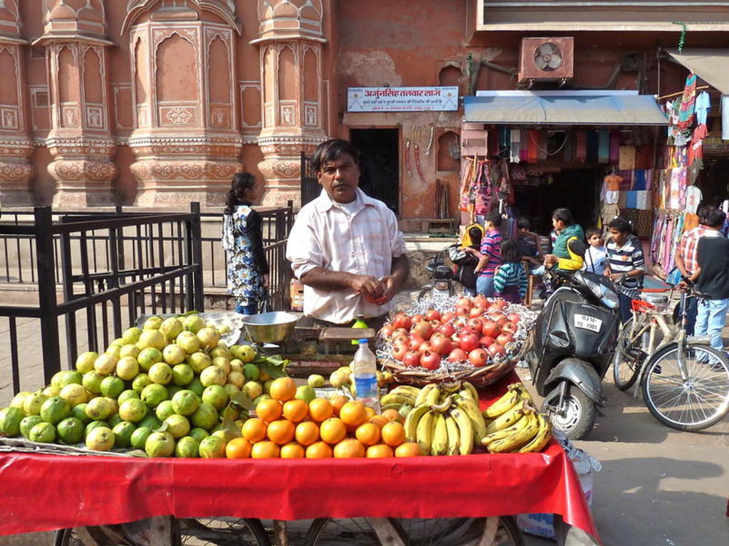 Fruitverkoper met kraam vol mango’s, sinaasappels, bananen en granaatappels op straatmarkt in Noord-India.
