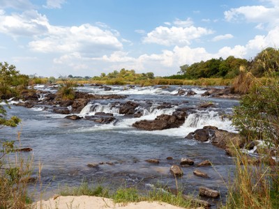 Stromende rivier met rotsen en kleine watervallen op de route Windhoek–Victoria Falls.