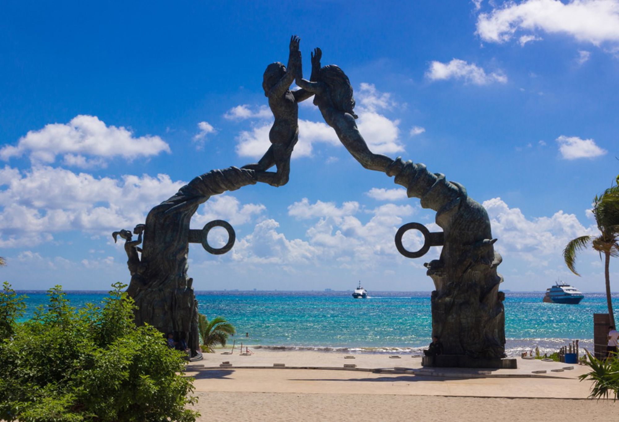 Bronzen Portal Maya-beeld bij het strand van Playa del Carmen, met uitzicht op de Caribische Zee.