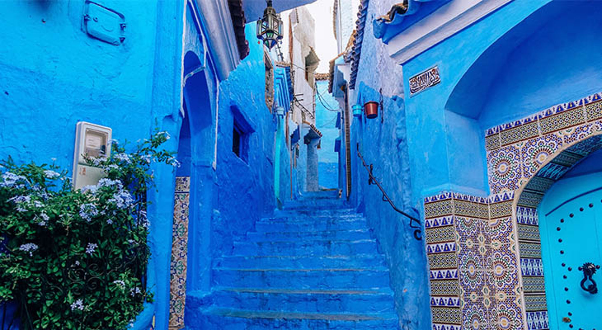 Blauw geschilderde straat met trappen en mozaïektegels in Chefchaouen, Marokko.
