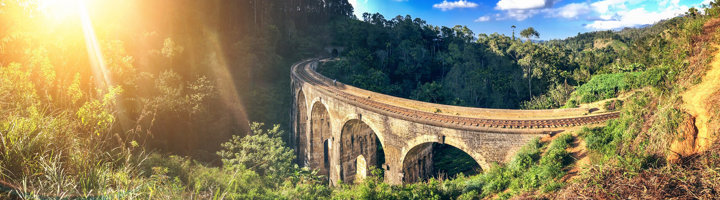 Negenbogenbrug bij Ella in Sri Lanka, spoorviaduct tussen groene heuvels in de zon.