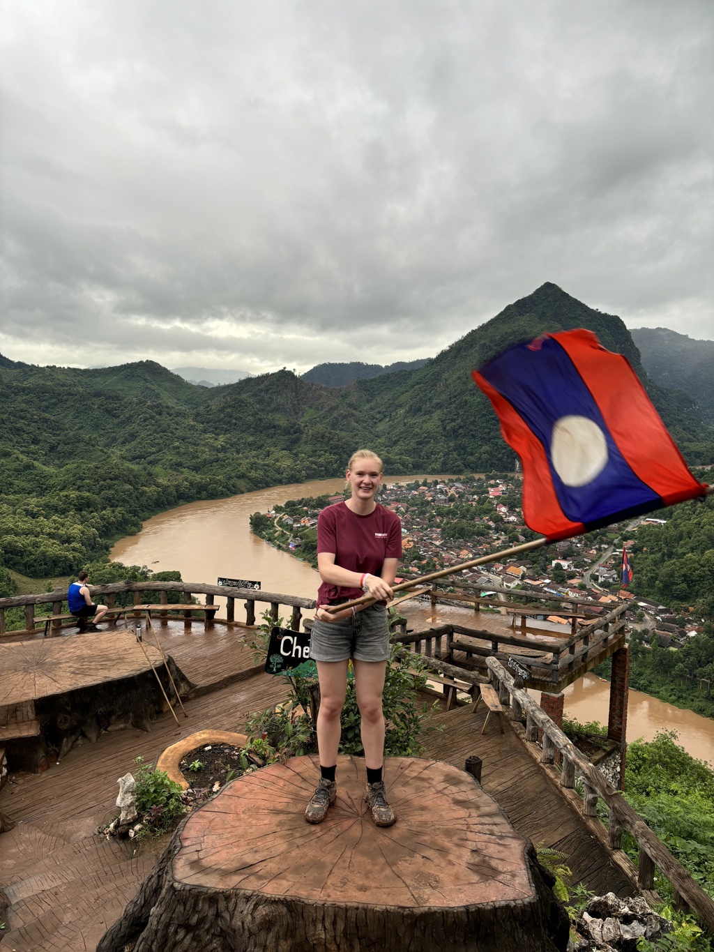 Reiziger met Laos-vlag bij uitzichtpunt over Luang Prabang en de Mekong, tijdens 22-35ers reis Thailand, Laos & Cambodja.