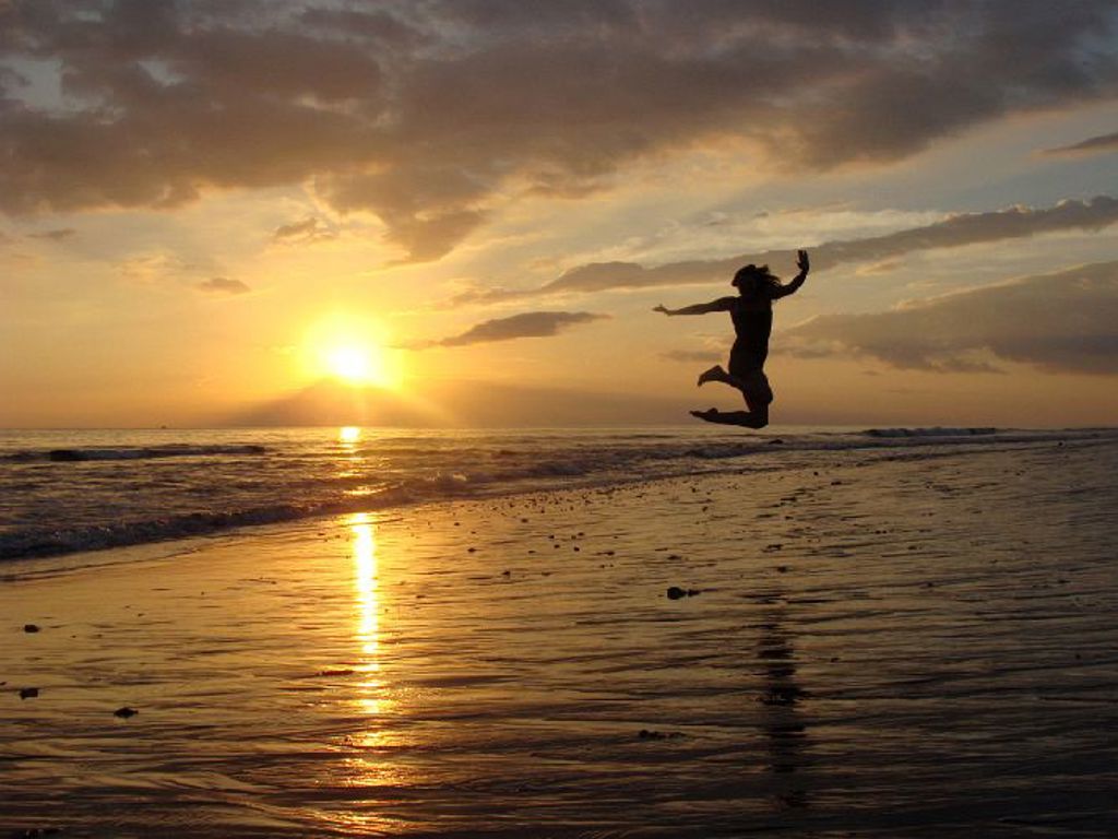 Silhouet van een springend kind op het strand bij zonsondergang op de Kleine Sunda Eilanden, Indonesië.