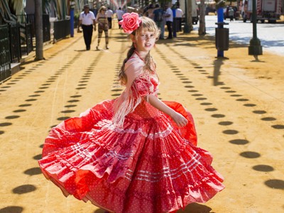 Meisje in rode flamencojurk met bloem in het haar op straat in Andalusië, Spanje.