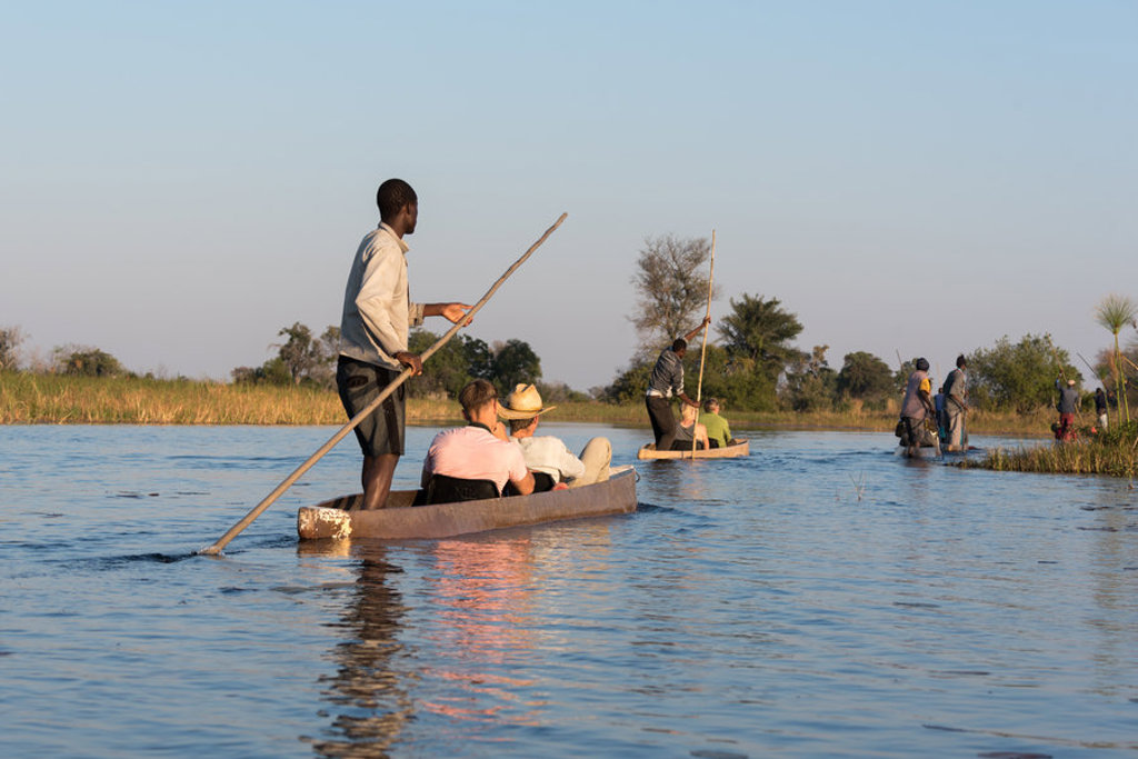 Mokoro-tocht met gidsen en reizigers door de Okavango Delta in Botswana tijdens familiereis Namibië, Botswana en Zimbabwe.