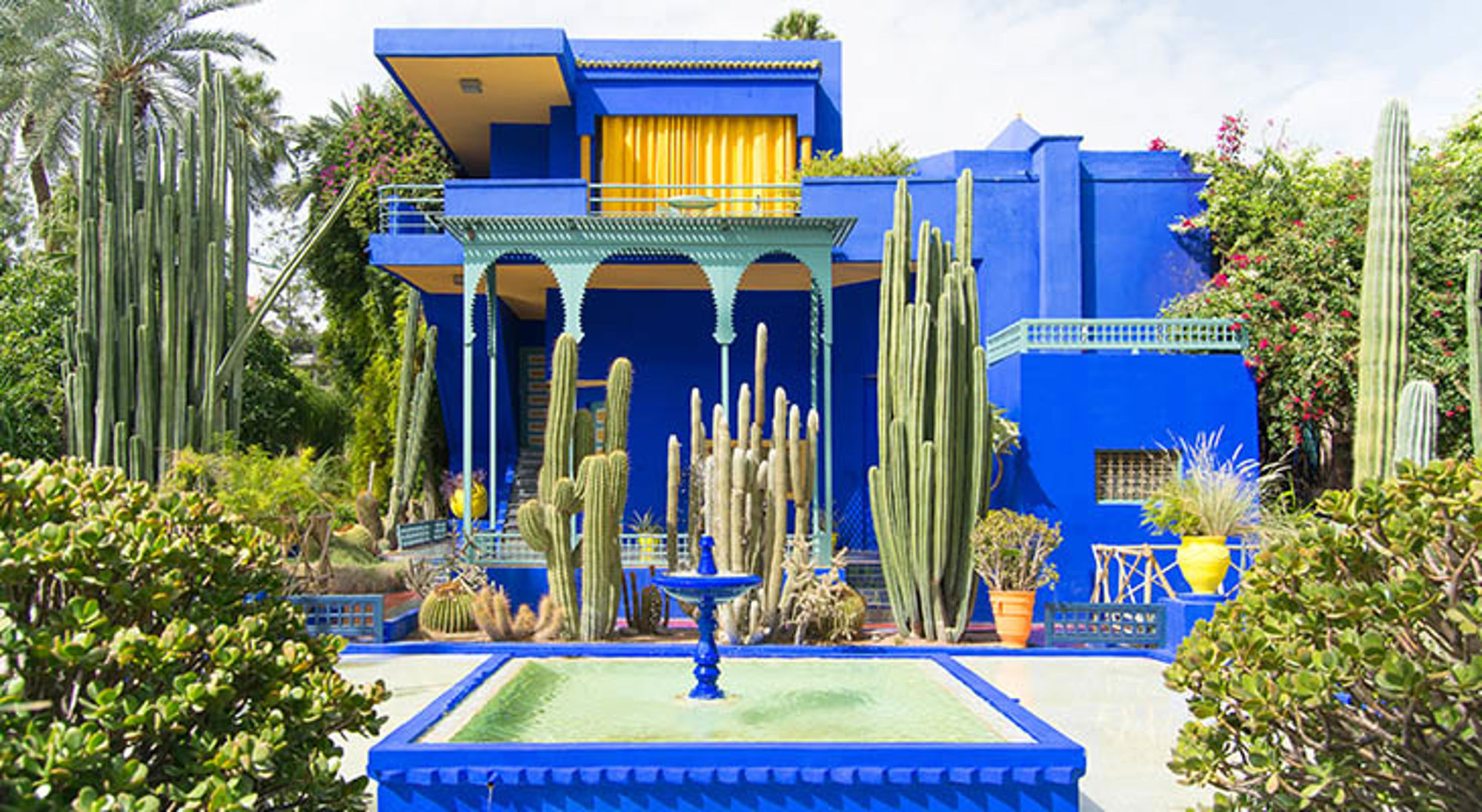 Jardin Majorelle in Marrakech met felblauwe villa, cactussen en fontein.