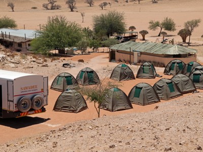 Kampeerterrein met safaritenten en reiswagen in de woestijn, route Victoria Falls - Windhoek.