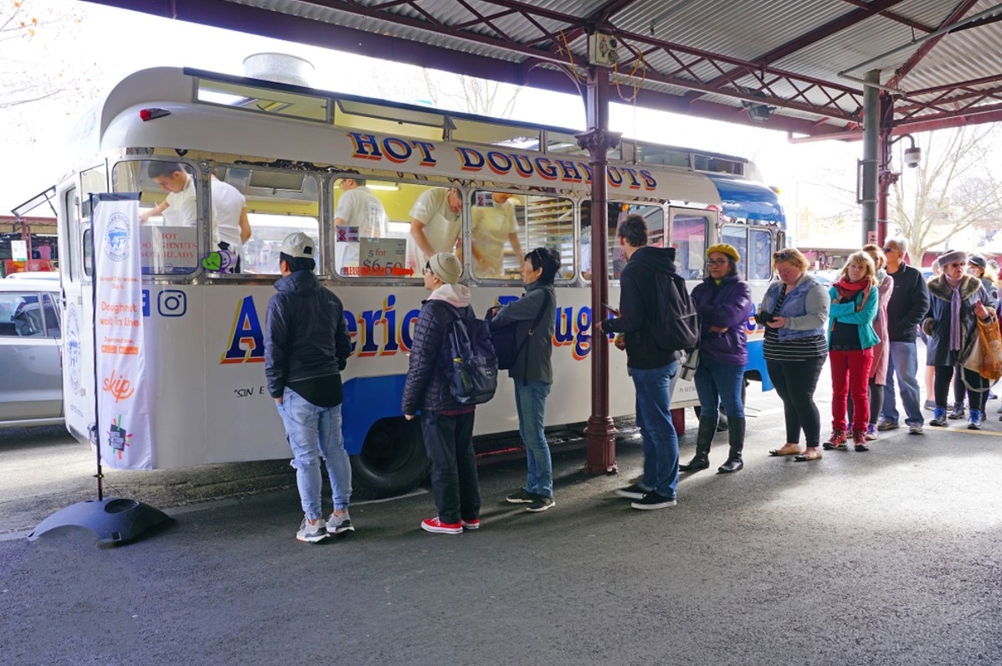 Bezoekers in de rij bij een foodtruck met warme donuts op een markt in Australië.