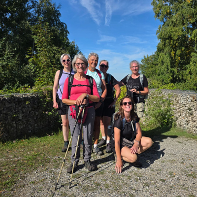 Wandelaars op de Dutch Mountain Trail, pauze op een zonnig bospad tussen stenen muren.