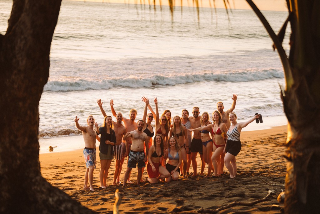 Groep 22-35ers op het strand in Costa Rica tijdens zonsondergang.
