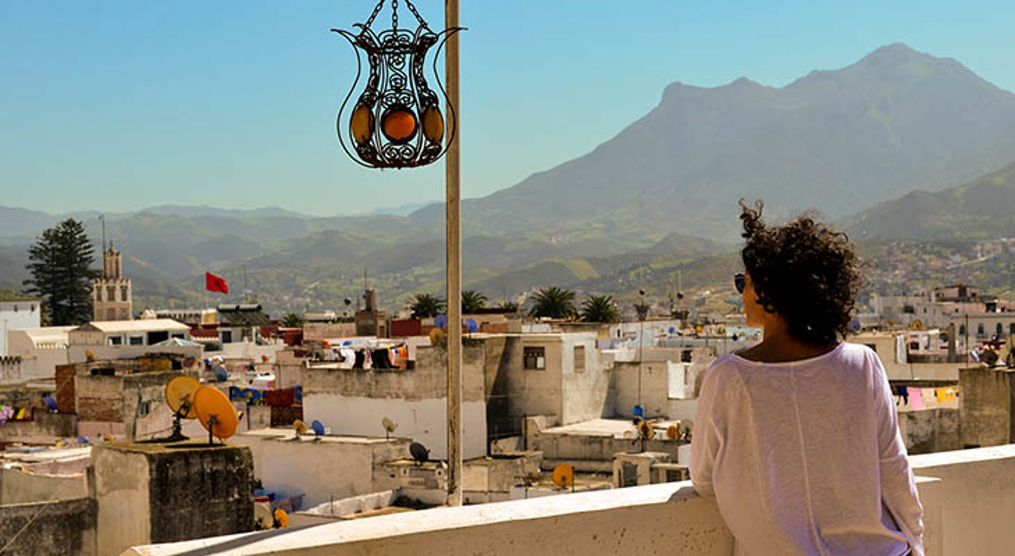Uitzicht over de daken van Chefchaouen met de Rifgebergte op de achtergrond, gezien vanaf een terras.
