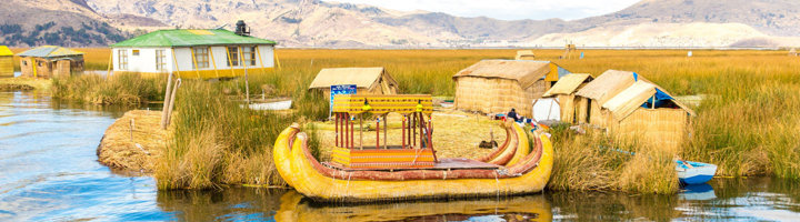 Rieten boot en rieten huisjes op de Uros-eilanden bij Puno op het Titicacameer, Peru.