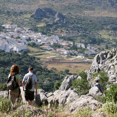 Wandelaars met rugzak in Andalusië met uitzicht op een wit dorp tussen bergen en rotsen.