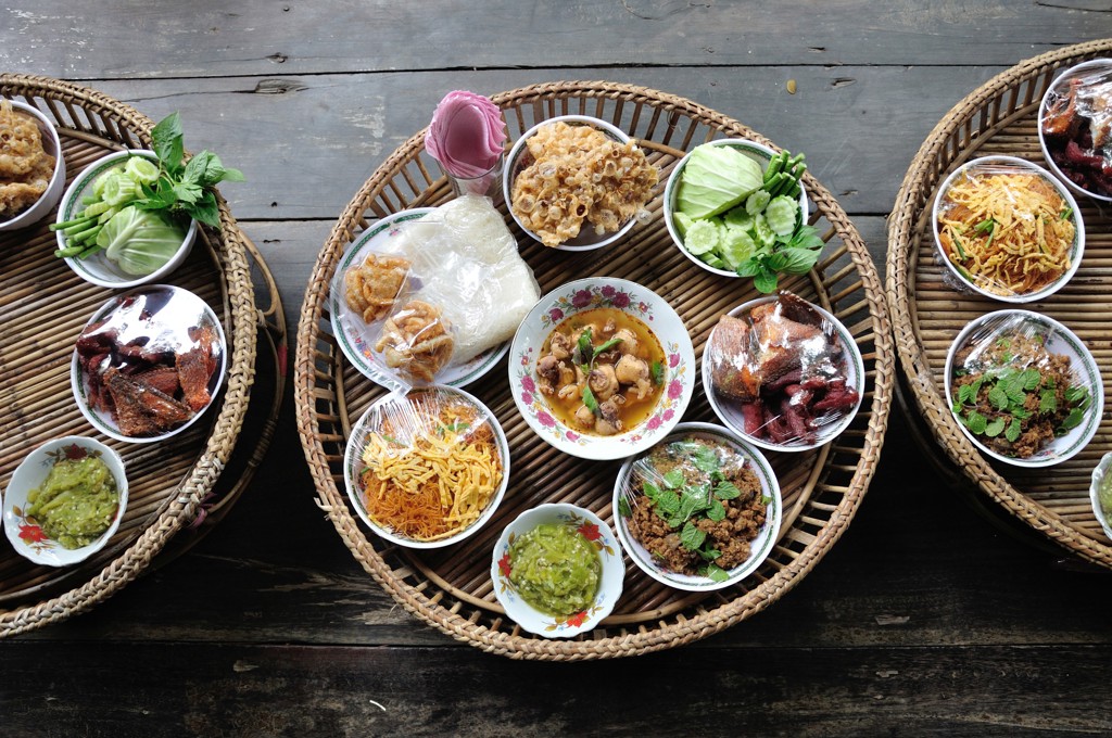 Thaise lunch met rijst, groenten en verschillende gerechten op rieten dienbladen tijdens groepsrondreis Singapore, Maleisië & Thailand.