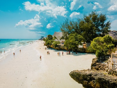 Wit zandstrand met turquoise zee en strandhutten op Zanzibar, onderdeel van de route Kenia & Tanzania.