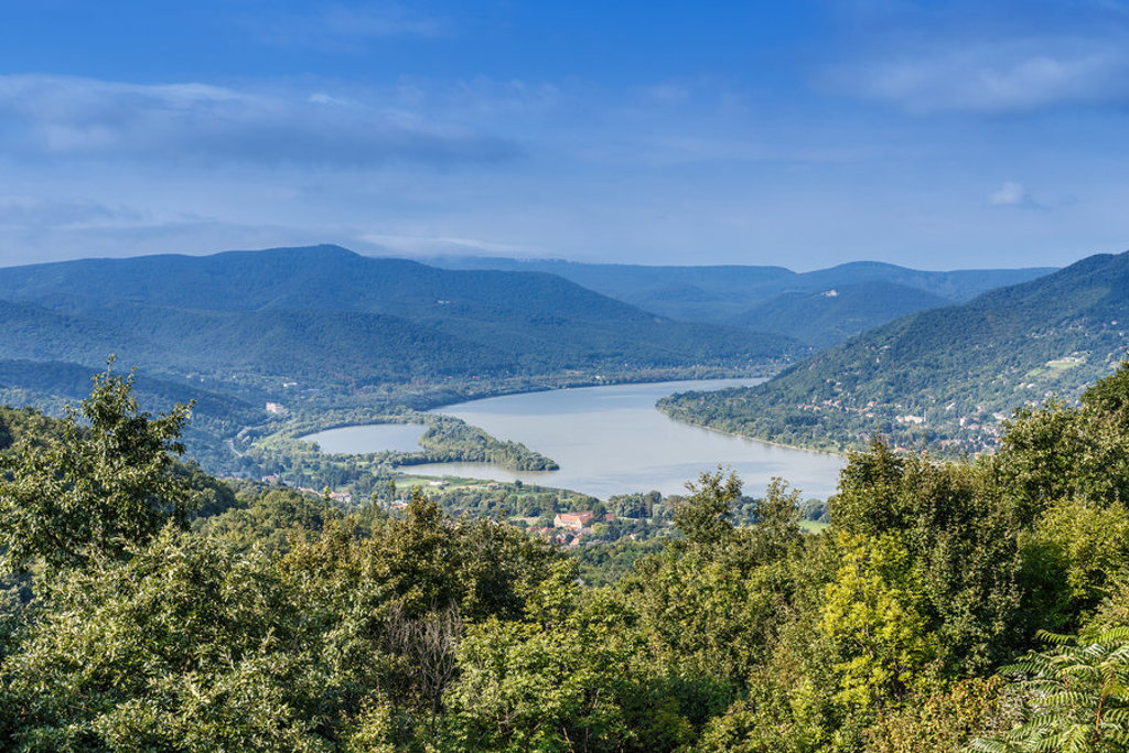Uitzicht op de Donau tussen groene heuvels en bossen tijdens een fietsvakantie langs de Donau.
