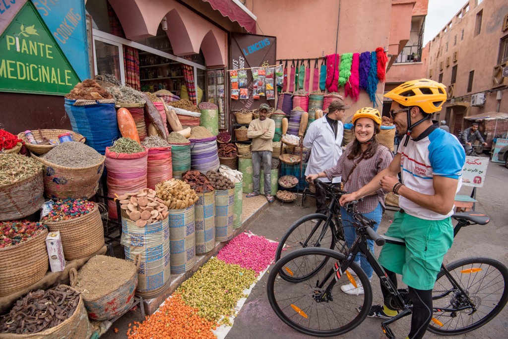 Fietsers bij een kleurrijke kruidenmarkt in Marokko tijdens een fietsvakantie.