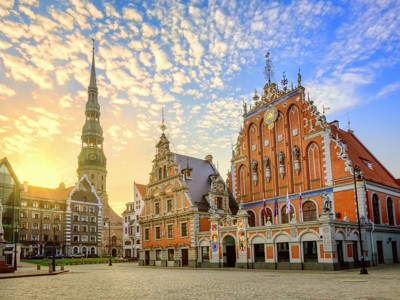 Zonsopkomst op het Stadhuisplein in Riga met het Zwarthoofdenhuis en de Sint-Pieterskerk, Route Baltische Staten.