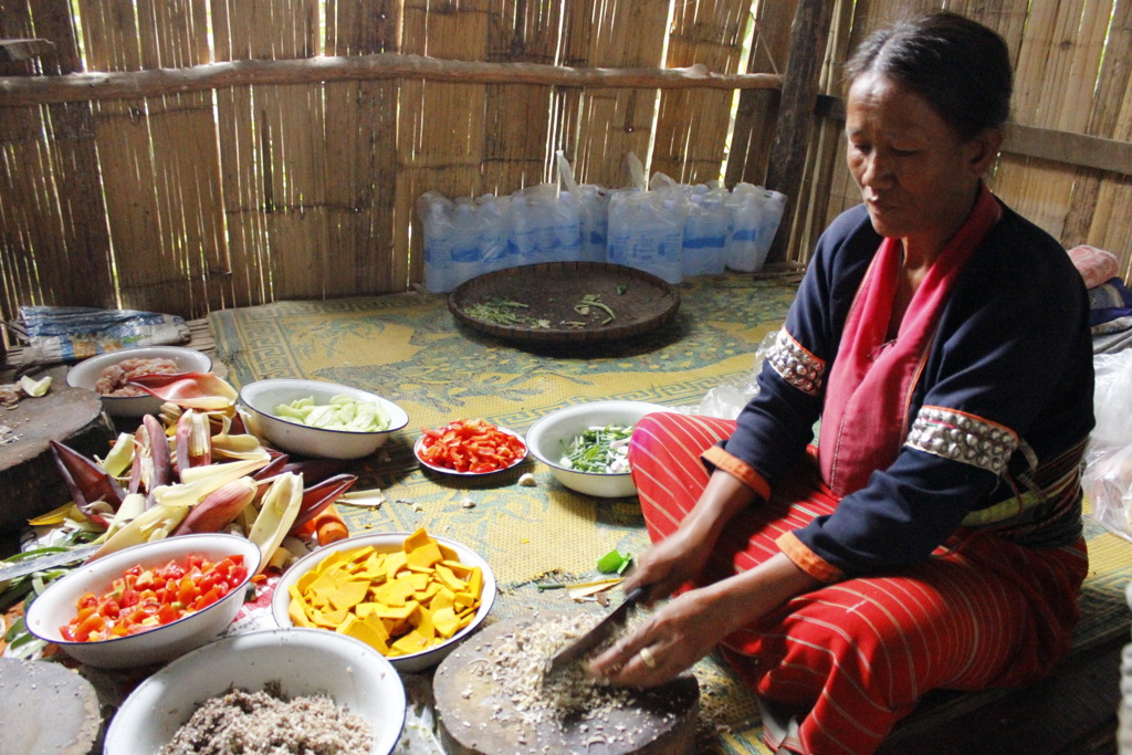 Thaise vrouw bereidt lokale maaltijd met verse groenten tijdens een groepsrondreis door Thailand.