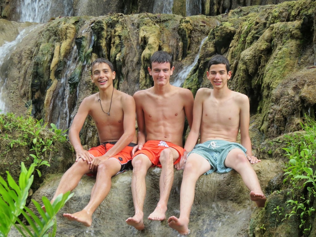 Drie tieners ontspannen bij een waterval tijdens een familiereis Mexico.