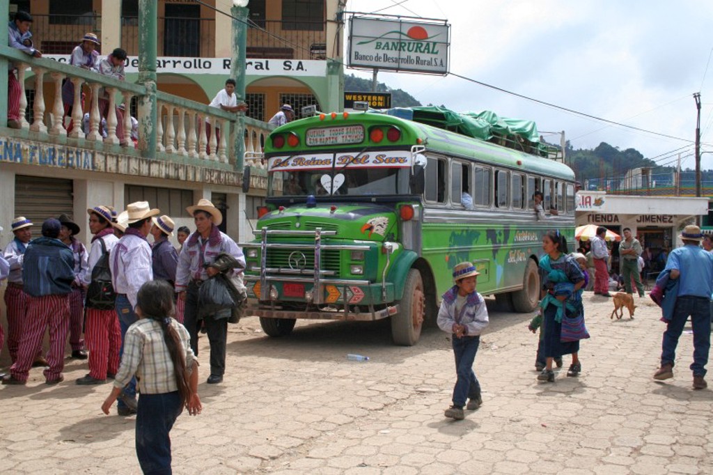 Groene chickenbus op een dorpsplein in Guatemala, tijdens groepsrondreis Mexico, Guatemala en Honduras.