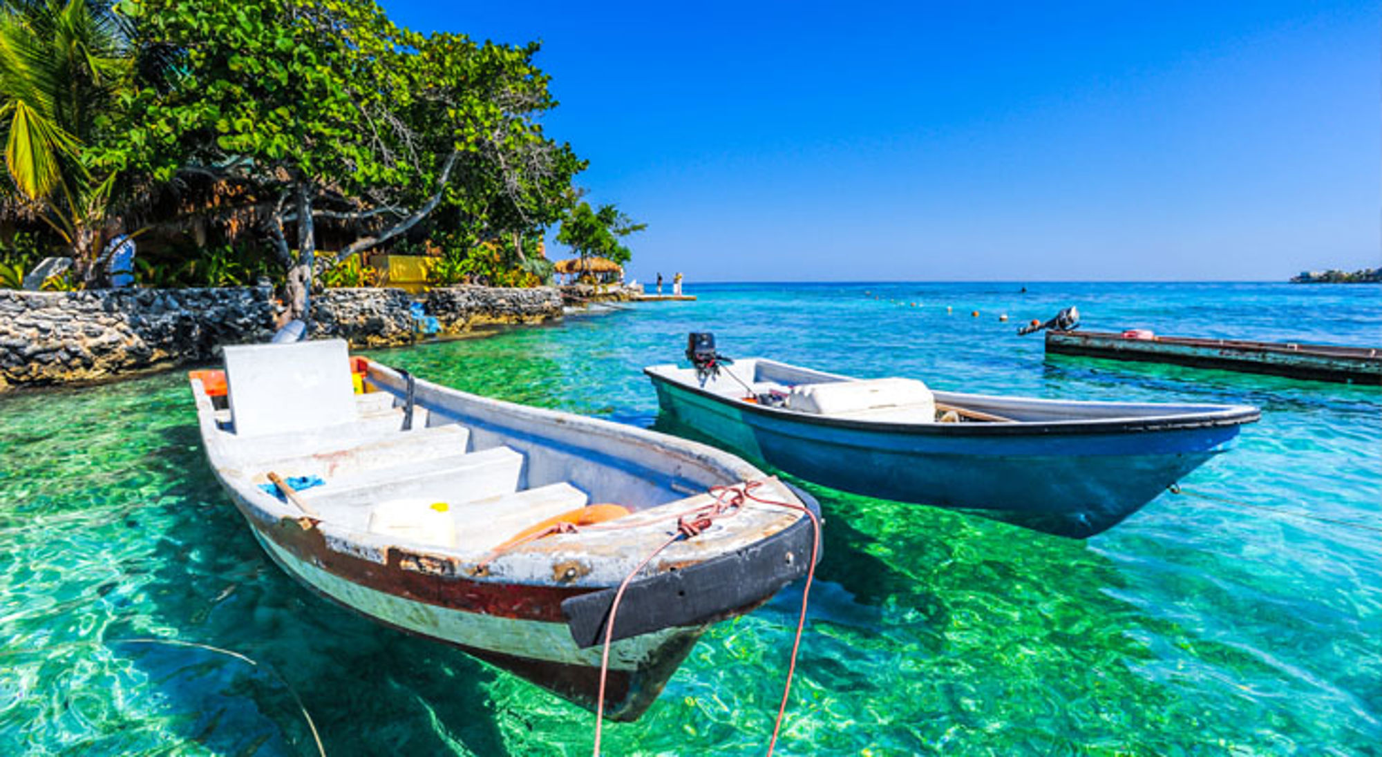 Bootjes in helder turquoise water bij een tropisch strand in Colombia.