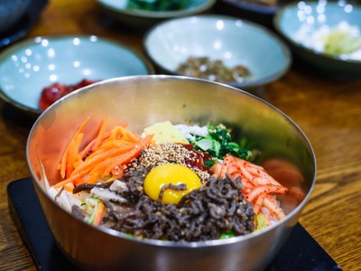 Bibimbap met rijst, groenten, sesam en eidooier in een metalen kom, Zuid-Korea.