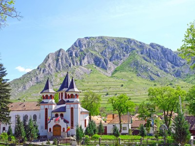 Kerk in Rimetea met de rotsen van Piatra Secuiului op de achtergrond, Route Roemenië.