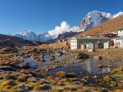 Lodges in Gorak Shep met beek en besneeuwde Himalayapieken tijdens de Route Nepal Everest Base Camp.