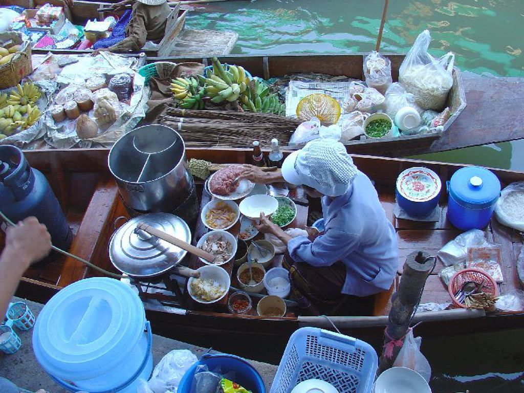 Kok bereidt eten op een drijvende markt in Thailand tijdens de familiereis Thailand Hoogtepunten.