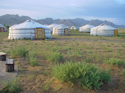 Mongoolse gers (joerts) in de steppe met bergen op de achtergrond.