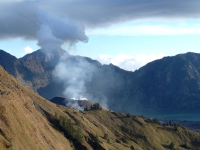 Rokende vulkaankrater bij Mount Rinjani op Lombok, met bergkam en kratermeer op de achtergrond.