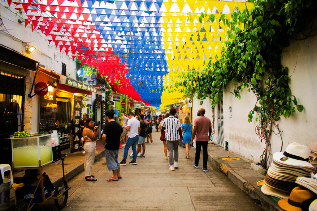 Kleurrijke straat in Cartagena, Colombia, met vlaggetjes boven de markt en reizigers tijdens een 22-35ers rondreis.