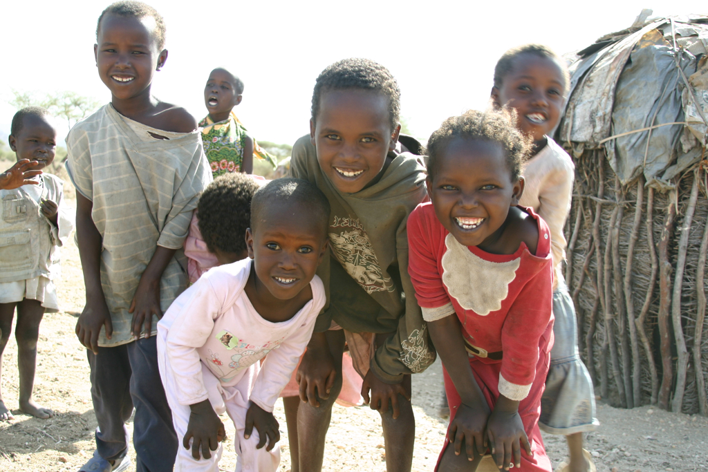 Lachende kinderen bij een traditioneel dorp tijdens familiereis Kenia en Tanzania.