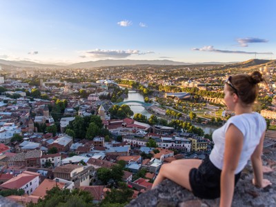 Uitzicht op Tbilisi met de Koera-rivier en de Vredesbrug vanaf een uitkijkpunt bij zonsondergang.