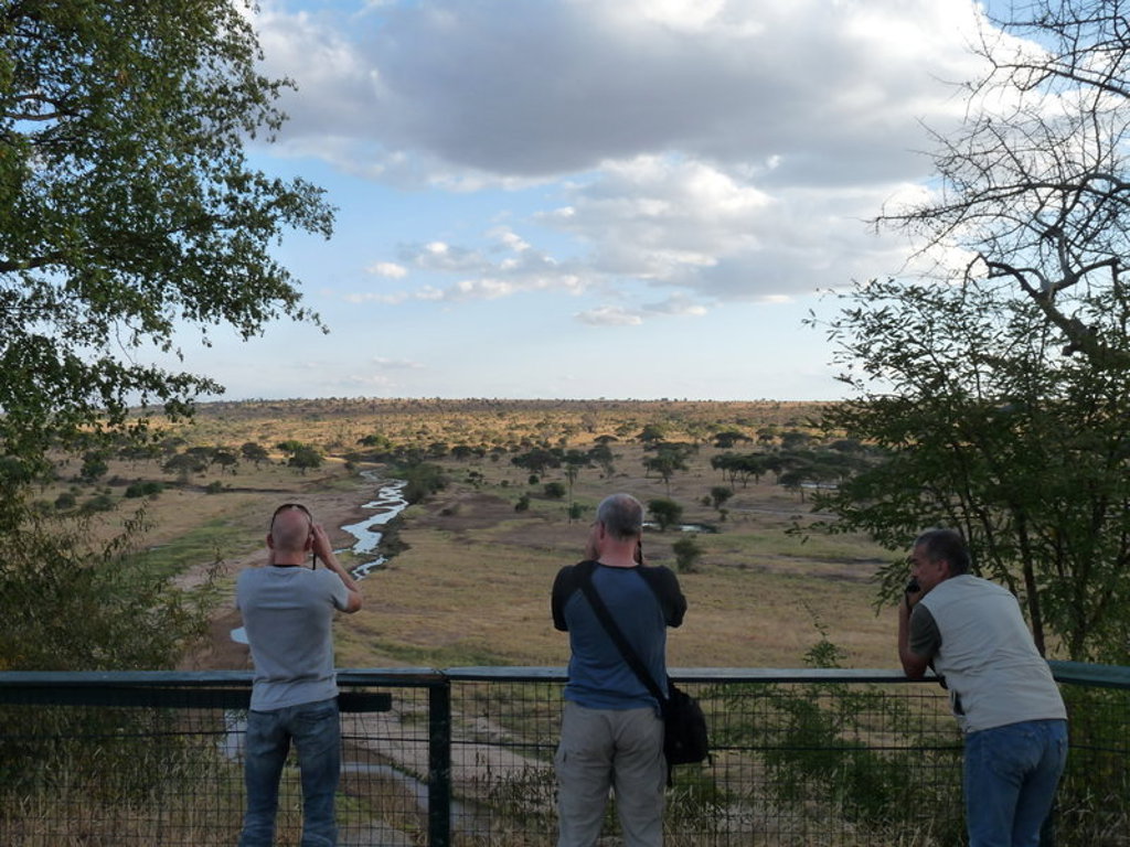 Reizigers kijken uit over de savanne in Kenia en Tanzania met een kronkelende rivier in de verte.