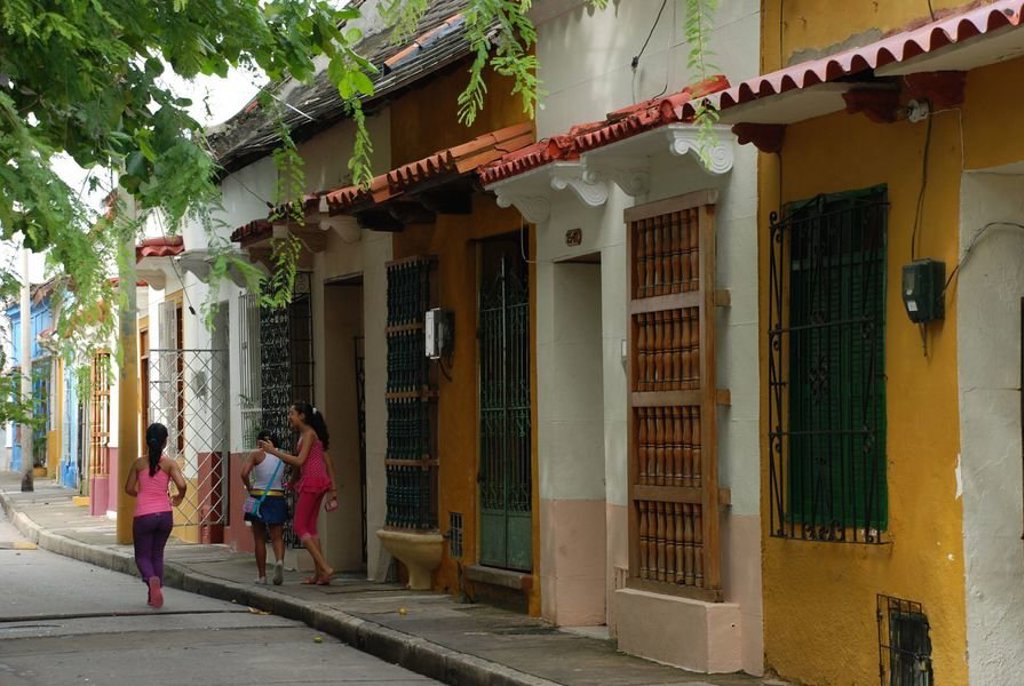 Kleurrijke straat met koloniale huizen en spelende kinderen in Colombia tijdens een groepsrondreis.
