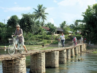 Fietstocht over een bamboebrug over de rivier tijdens de route Laos & Cambodja.