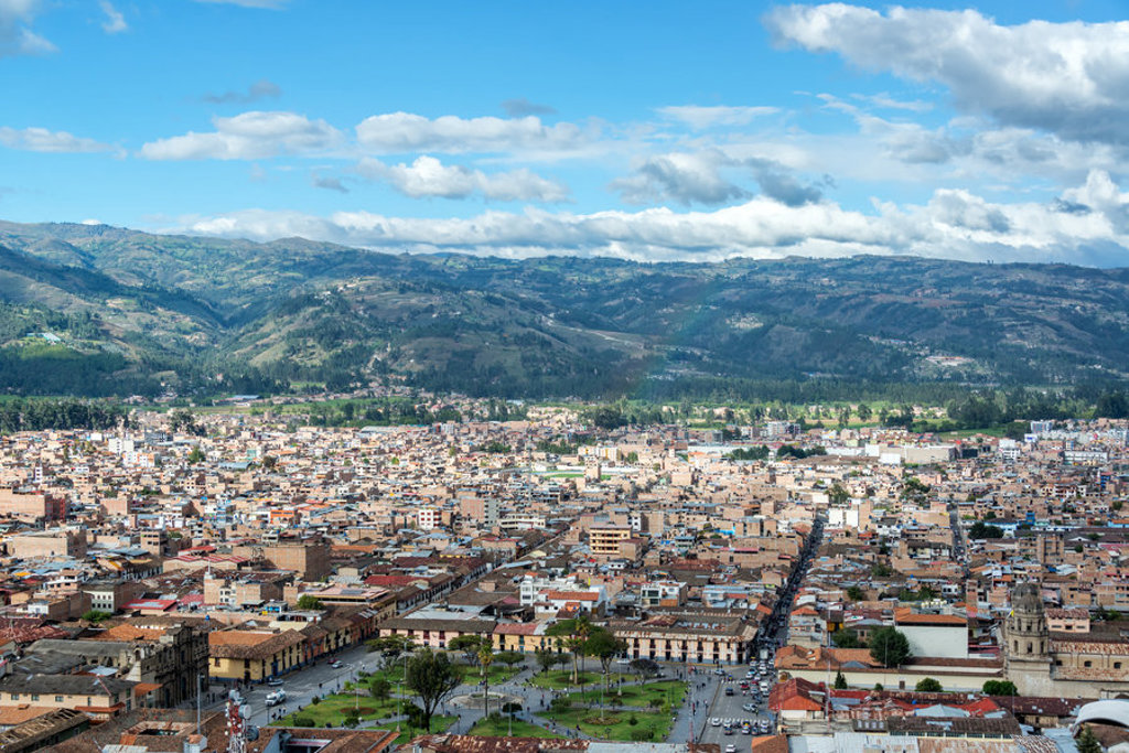 Panorama van Cajamarca in Noord-Peru met stadscentrum en groene bergen onder een blauwe lucht.