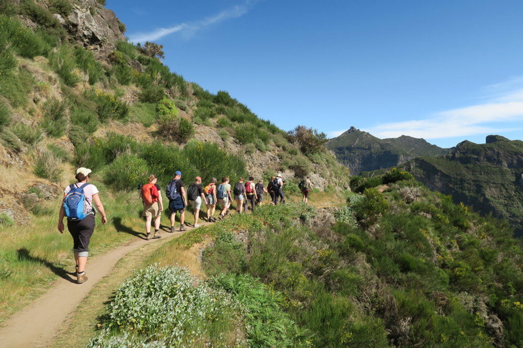 Wandelaars op bergpad met uitzicht over de groene bergen van Madeira tijdens een wandelvakantie.